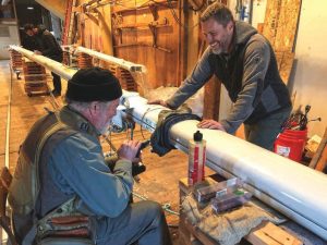 Rigger Brion Toss (seated) drills and taps a new hole inthe mast while Marty smiles at one of his jokes. In the
background, Ian Weedman inspects the spreader tang.