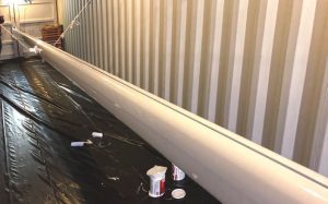 The newly painted mast hanging in the shippingcontainer.
