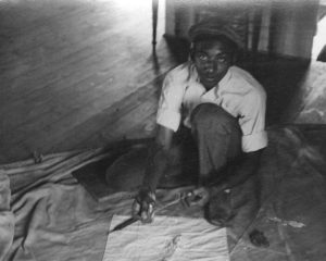 A young Downes Curtis patches a sail. By H. Robins Hollyday. Photograph from the collection of the Talbot Historical Society.